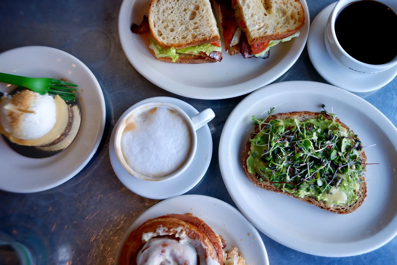 Top view of a breakfast table with coffee, pastries, and avocado toast.